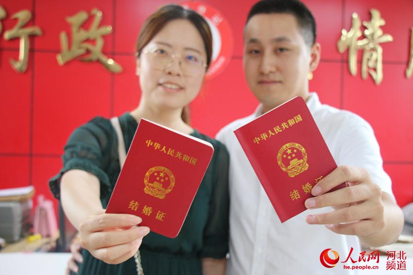 图为8月7日，在河北省广平县民政局婚姻登记处，一对新人领取结婚证后在颁证大厅拍照留念。程学虎摄