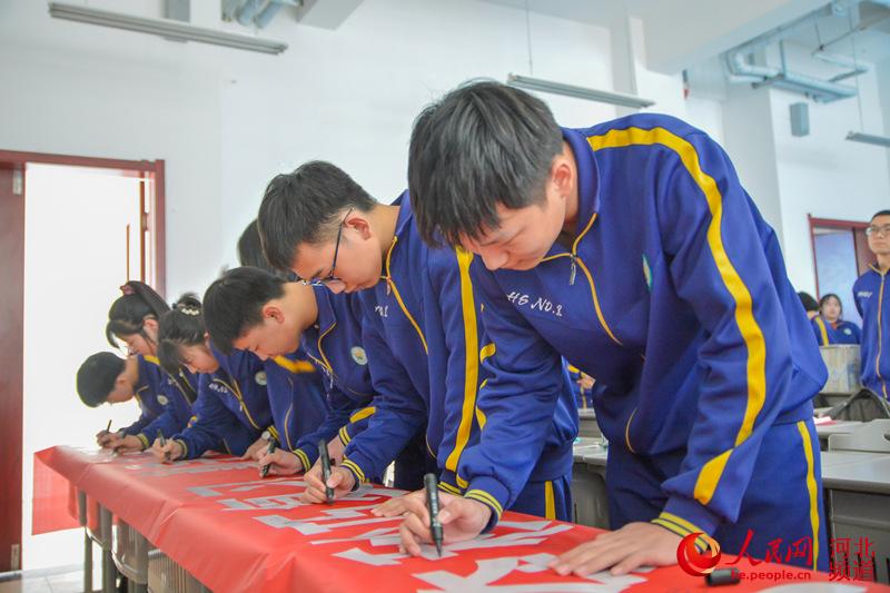 2021年3月3日，河北省邯鄲市邯山區第一中學學生在“百日”誓師活動的橫幅上簽名。 李昊攝