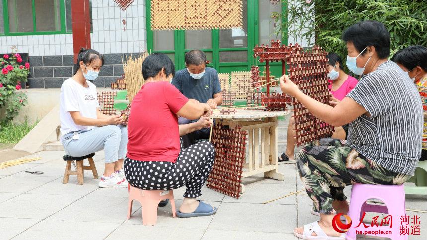 王学信将高粱秸秆编织工艺传授给村民共同致富。 田威摄