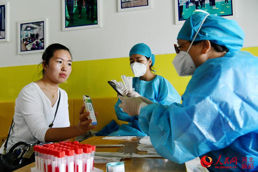 8月24日，在河北省廣平縣第四幼兒園臨時核酸檢測採樣點，幼兒教師掃碼登記進行核酸檢測採樣。程學虎攝