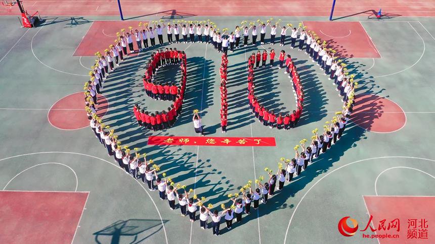 孩子們在操場上擺出“愛心+9.10”造型，祝福老師節日快樂。 杜昕雨攝