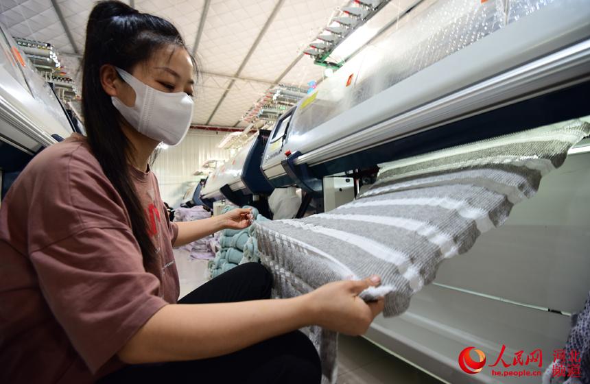 河北青縣某針織企業車間生產線上，工人為毛衣剪裁成片。 張鵬攝