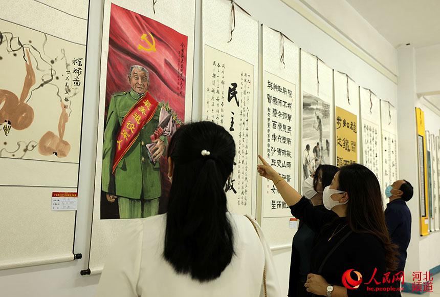 邢台市廣宗縣2021年國慶節教育系統師生書畫展上，教師在欣賞參展的書畫作品。 王壘攝