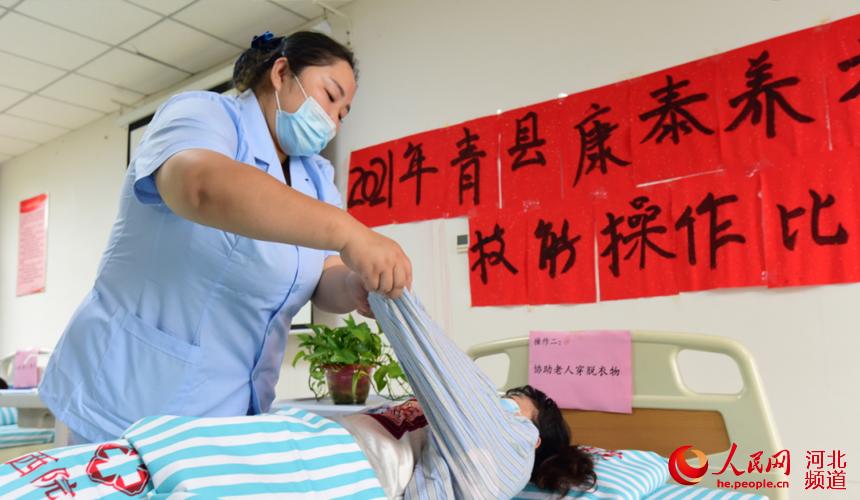 青县康泰养老护理中心养老护理员大赛比赛过程中,护理员在进行“协助‘老人’穿脱衣物”操作。 张鹏摄