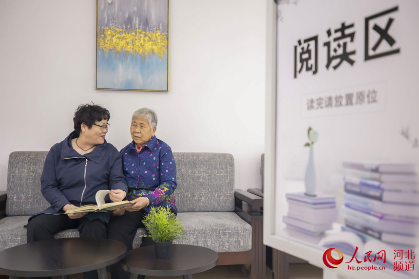 老人在河北省唐山市丰南区向日葵居家养老服务站阅读区内看书交流。 毕帅摄