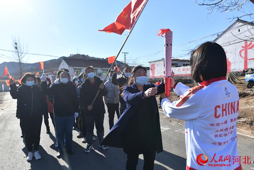 11月22日，來自木廠口鎮北營村的火炬手孟凡榮（左）和大學生志願者代表闞澤慧正在接傳火炬。 梁玉水攝