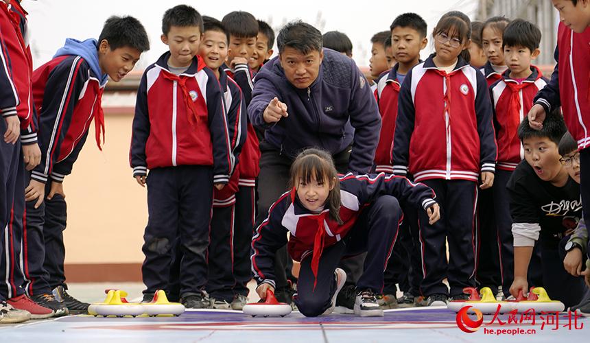 河北省孟村回族自治縣育才小學學生在教練的指導下練習地板冰壺運動。 張曉鵬攝