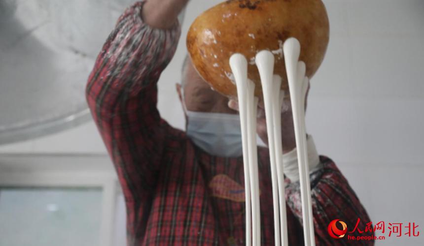 12月10日,灵寿县塔上镇正国种植专业合作社,工人们正在手工漏粉条。 杨敏摄