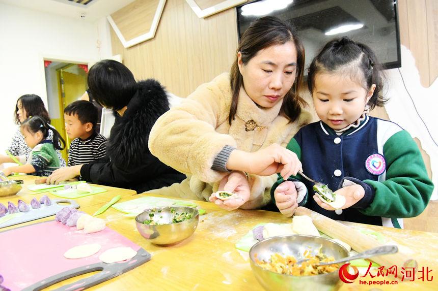 邯鄲市廣平縣第四幼兒園小朋友在老師的指導下學包餃子。 程學虎攝