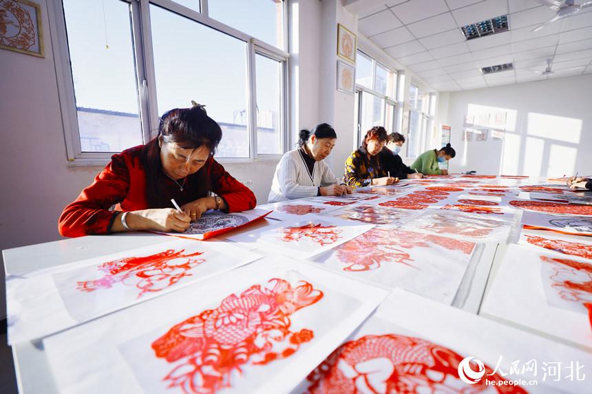 在河北省唐山市丰南区青年路街道银城花园社区剪纸室，社区的剪纸爱好者们正在创作虎年题材剪纸作品。毕帅摄