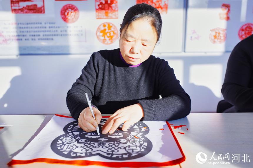 在河北省唐山市丰南区青年路街道银城花园社区剪纸室，社区的剪纸爱好者们正在创作虎年题材剪纸作品。毕帅摄