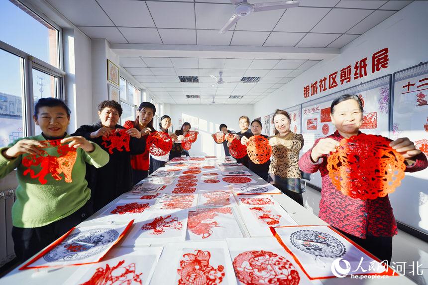 在河北省唐山市丰南区青年路街道银城花园社区剪纸室，社区的剪纸爱好者们正在展示虎年题材剪纸作品。毕帅摄