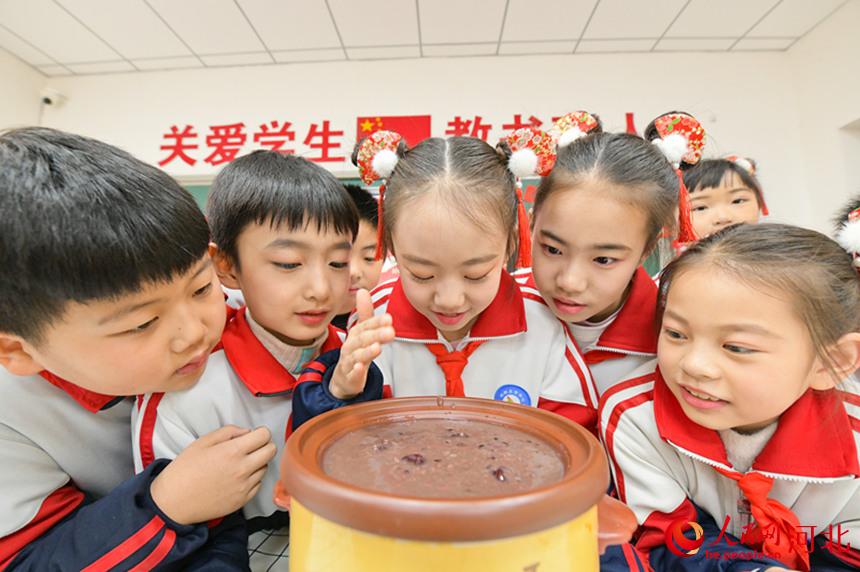河北省邯郸市冀南新区铁路小学举行“品尝腊八粥、学习民俗文化”活动。孩子们和老师一起制作腊八蒜。 杜昕雨摄