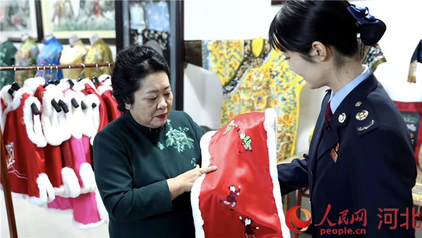 京绣传承人梁淑平向税务干部展示生产的2022北京冬奥会京绣产品。 定兴县委宣传部供图