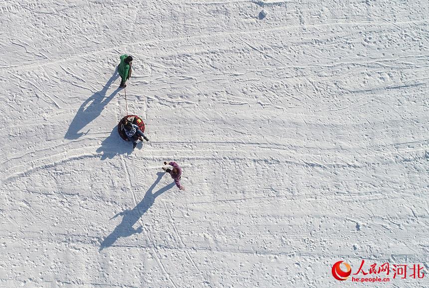 游客拉著雪圈在滑雪場走過。 張旭攝