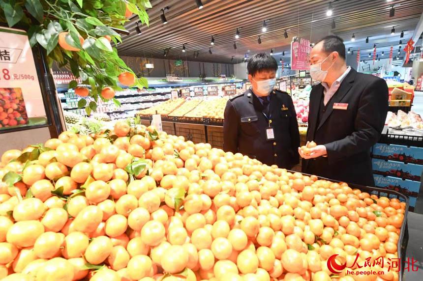 永清县市场监督管理局工作人员对超市水果进行检查。  刘欣羽摄
