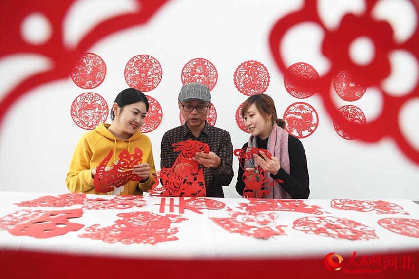 在河北省唐山市豐潤區太平路街道同安社區，剪紙藝人在教居民創作虎主題剪紙作品。 朱大勇攝