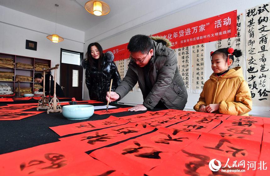 1月25日，在河北省遷安市扣庄鎮新時代文明實踐所，書法志願者正在書寫春聯。 梁玉水攝