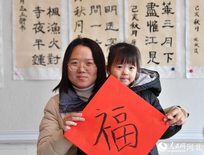 1月25日，在河北省遷安市扣庄鎮新時代文明實踐所，志願者張玉俠和女兒展示一起寫的“福”字。 梁玉水攝