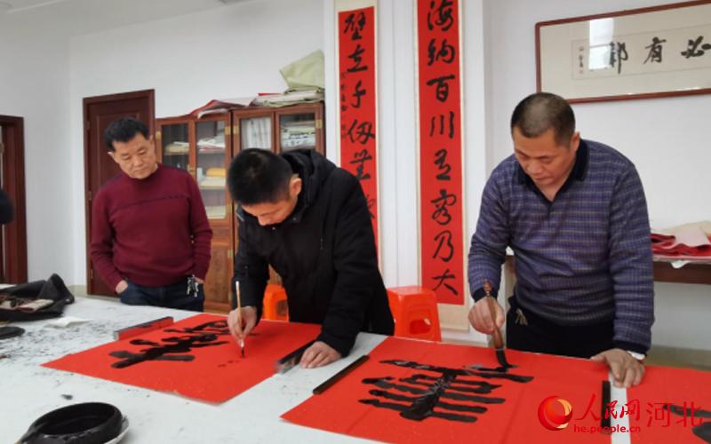 活动现场，东光县书法家正在为百岁老人们写“寿”字。 王文瑞摄