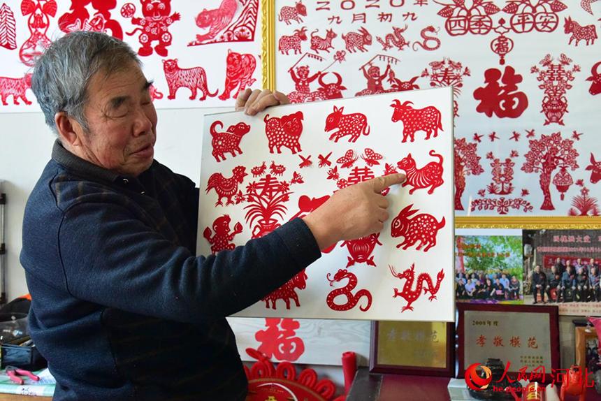 1月27日,72歲的剪紙藝術愛好者姚家貴老人,正在向我們展示剪紙作品。 張美娜攝