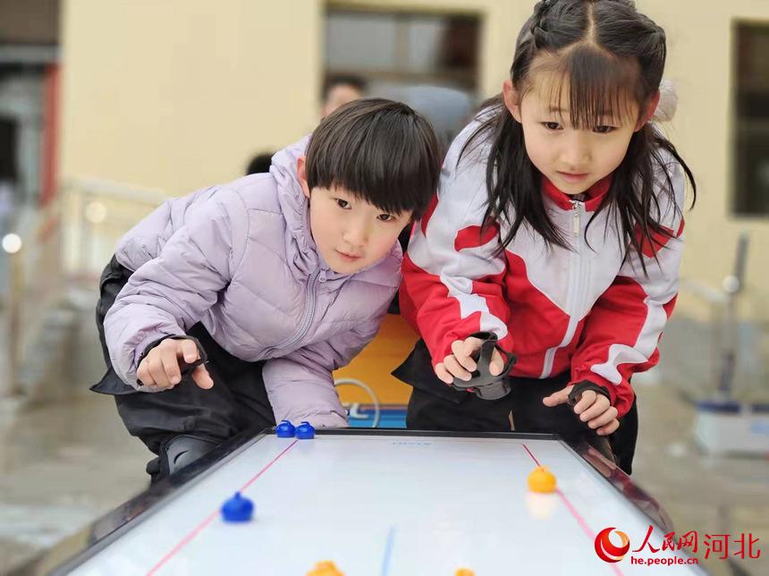 在河北邱縣城區街道辦廣場，孩子們在體驗桌上冰壺運動。霍飛飛攝