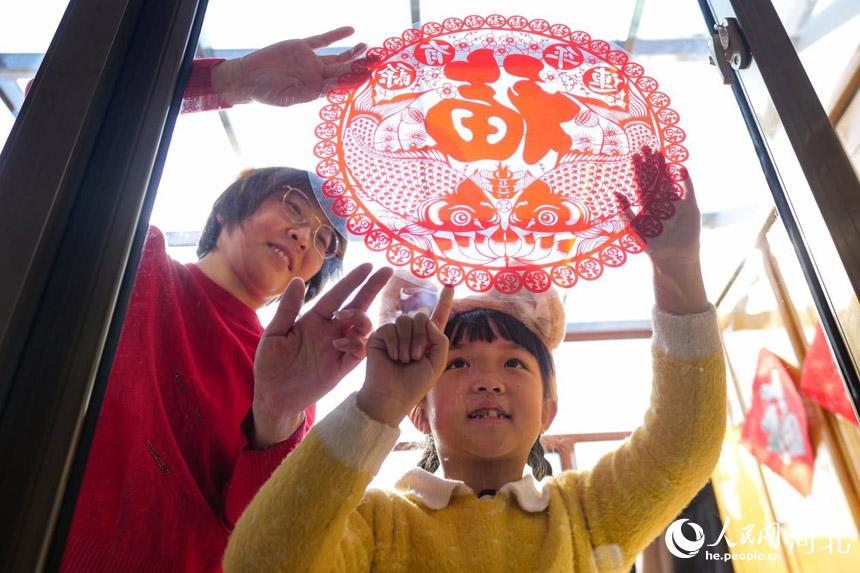 在河北省唐山市丰南区胥各庄镇岭子上村,村民正在自家抗震房里贴福字。 崔光摄