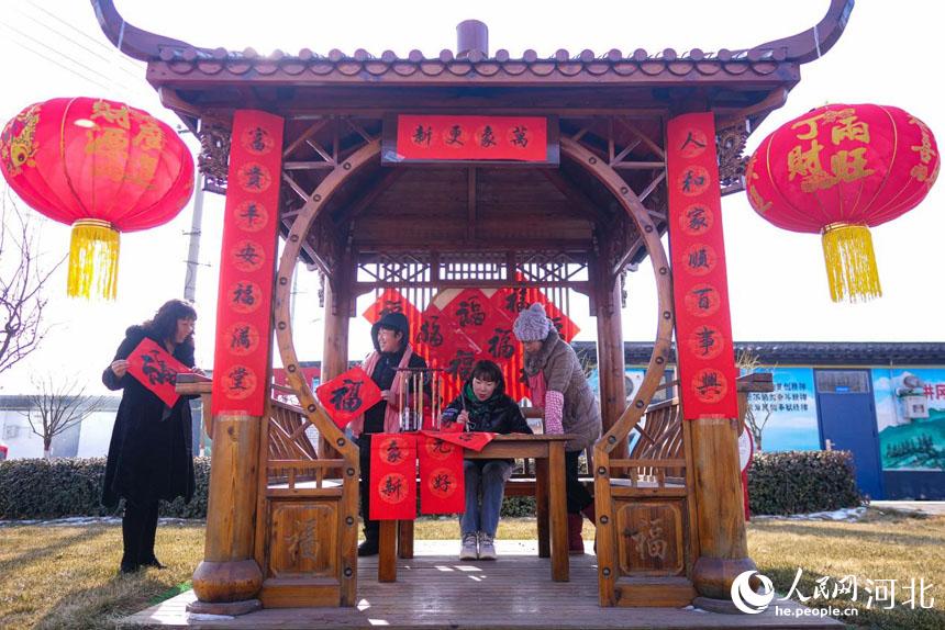 河北省唐山市丰南区胥各庄镇的书法爱好者正在为搬进抗震房的领子上村村民写福字。 崔光摄