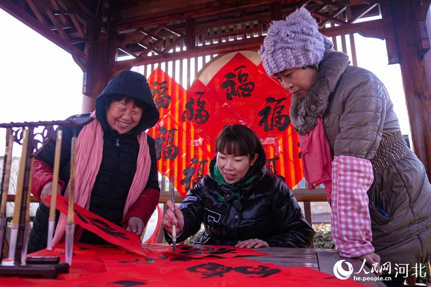 河北省唐山市丰南区胥各庄镇的书法爱好者正在为搬进抗震房的领子上村村民写福字。 崔光摄