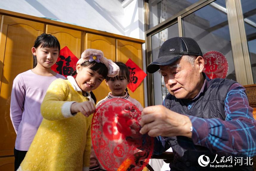 在河北省唐山市丰南区胥各庄镇岭子上村,村民正在自家抗震房里贴窗花。 崔光摄