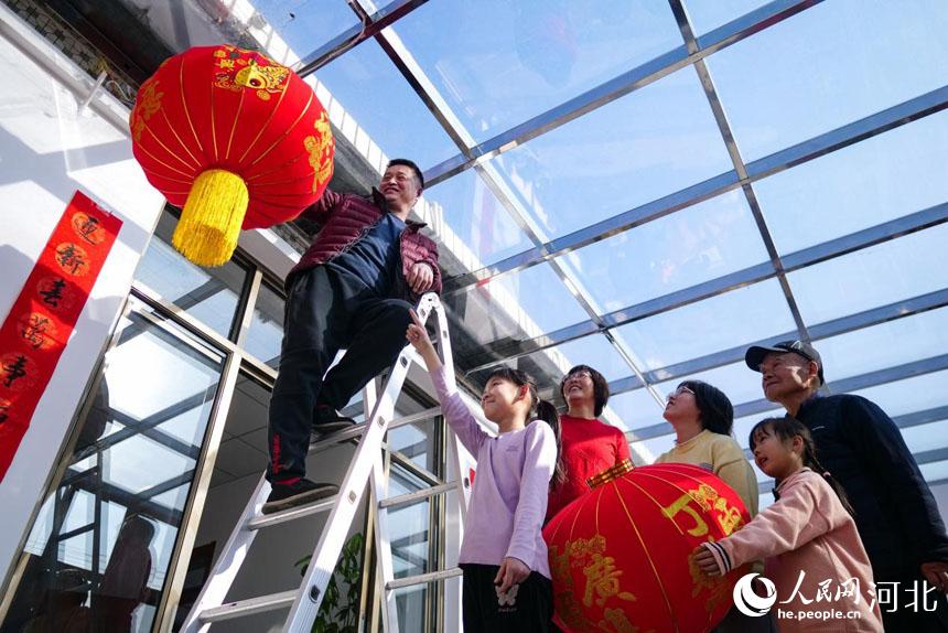 在河北省唐山市丰南区胥各庄镇岭子上村,村民正在自家抗震房里挂灯笼。 崔光摄
