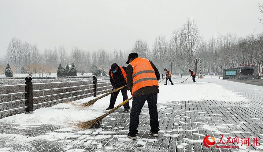 “城市美容師”冒雪清掃。 李月英攝