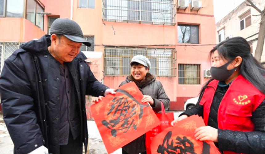 在文安县文安镇一所居民小区，志愿者向小区业主赠送春联。 王晖摄