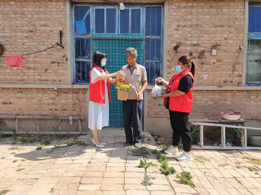 东光县东光镇新时代文明实践中心的志愿者将端午花束和热气腾腾的粽子送到独居老人手中。 牛邡摄