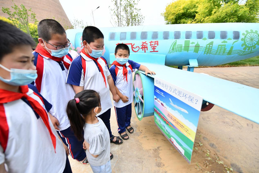 在河北省迁安市鑫达工业旅游园低碳园内，小朋友在废钢铁制成的“低碳”飞机前学习低碳知识。 梁玉水摄