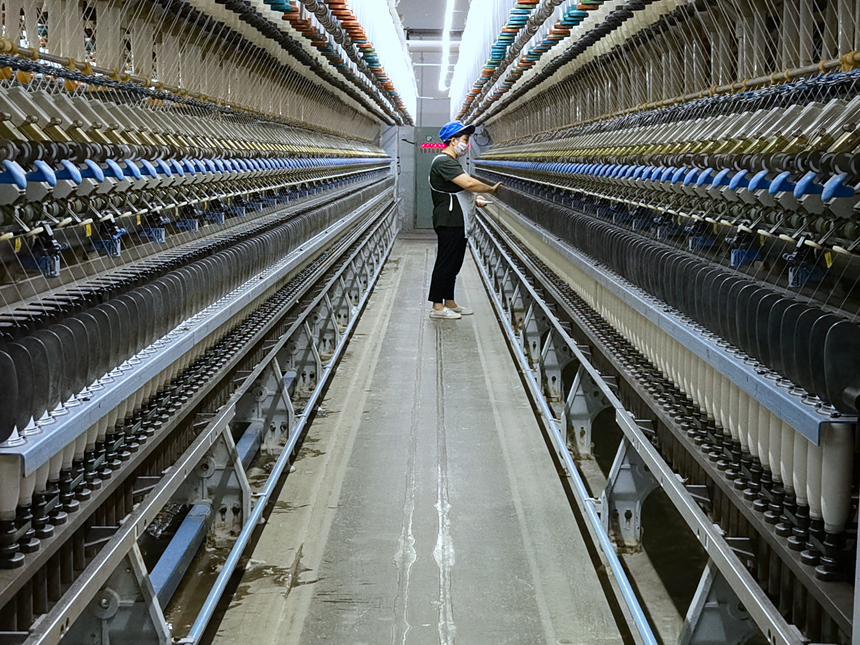 河北省东光县纺织企业内，技术工人在纺纱车间作业。赵越摄