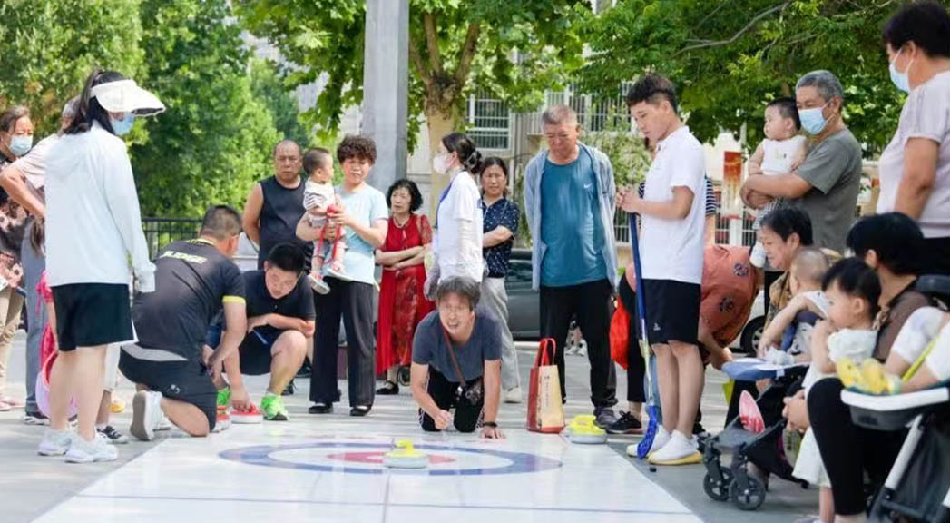 教练员带领社区居民学习陆地冰壶。 董浩佳摄