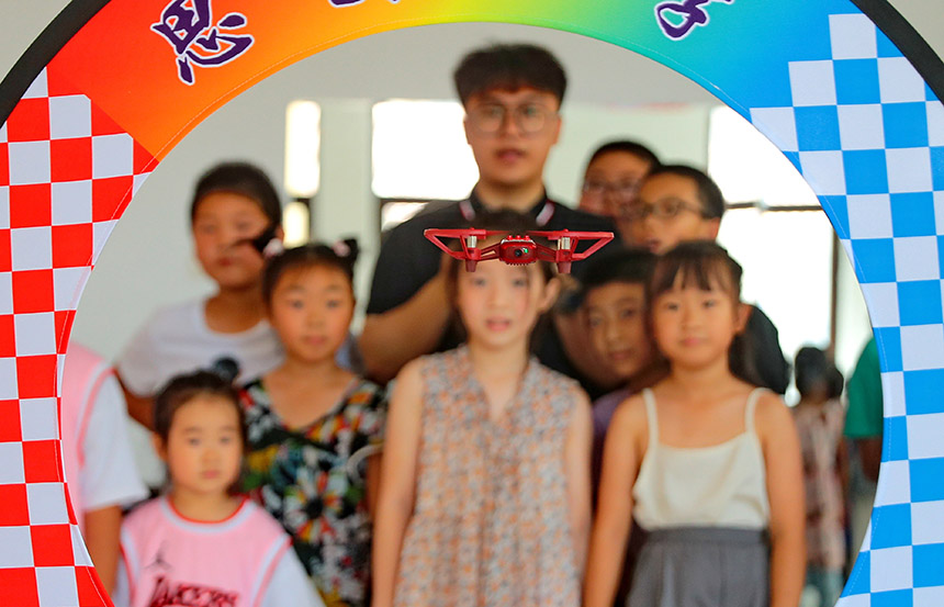  2022年7月19日，河北省秦皇岛市海港区白塔岭街道秦皇半岛第二社区内，小朋友正在观看“无人机穿越飞行”。 曹建雄摄