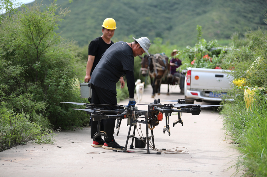 在石家庄市井陉县吴家窑乡长峪村荒山造林现场，工作人员在为无人机换电池。王保龙摄