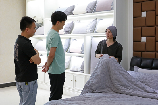 河北卡缦纺织品制造有限公司设计总监史树雷向客户介绍尼帝柔面料床品。　冉宁摄
