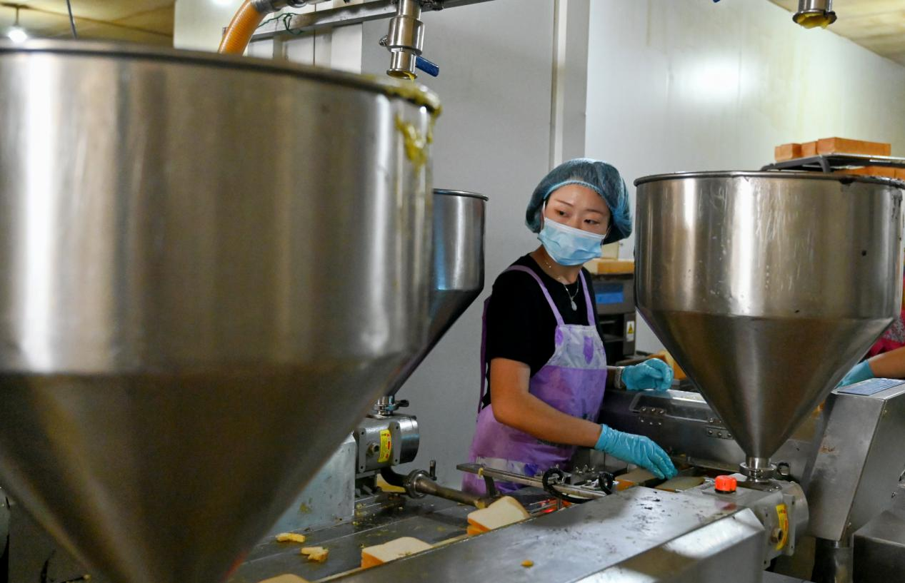 在盐山县东帽圈村一家面包加工厂，工人正在将蛋液加入面包。刘蒙蒙摄