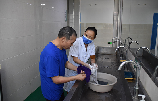 在中心生活区，工作人员正在协助患者洗涤衣物。张磊摄