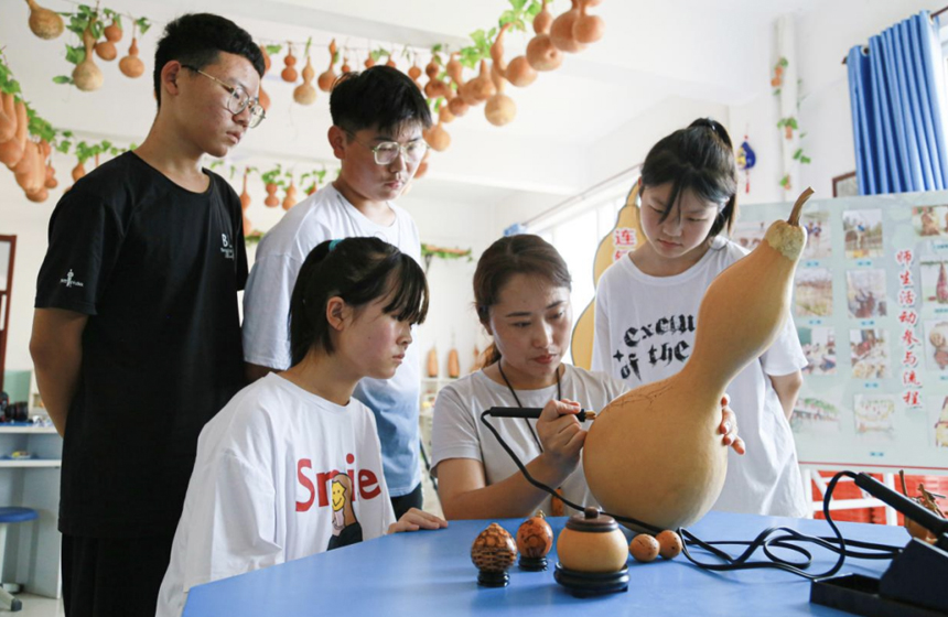 老师正在为孩子们示范葫芦烙画的基本手法。陈英华摄