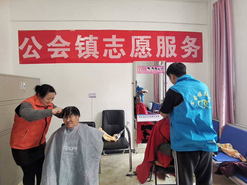 张北县公会镇幸福港湾养老院内志愿者们为老人免费理发。石炎夏摄