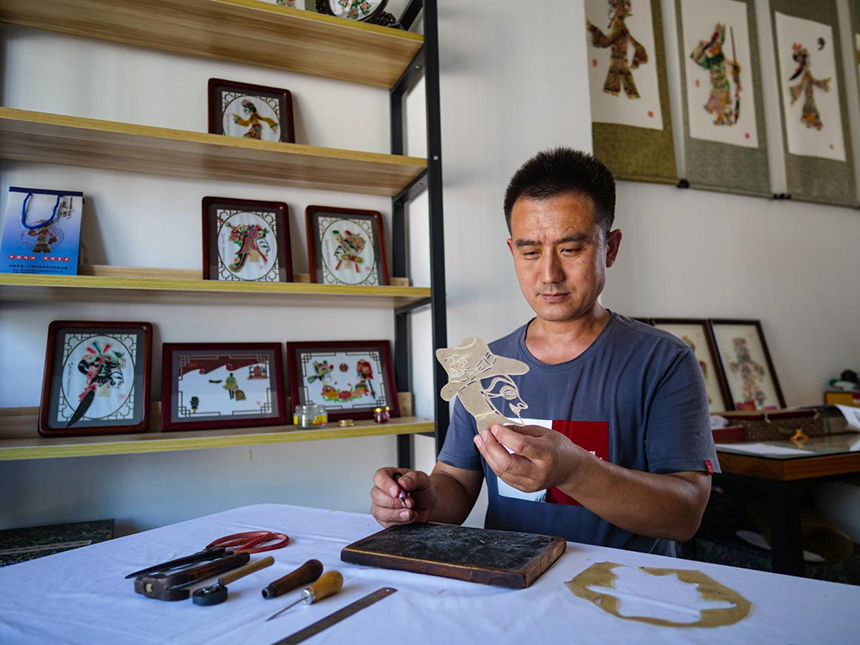 唐山市丰南区皮影雕刻艺人杨玉辉正在雕刻影人。崔光摄
