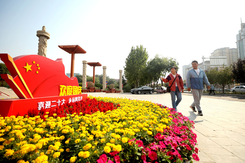 市民在河北省隆尧县唐尧公园花坛前散步。 陈昊摄