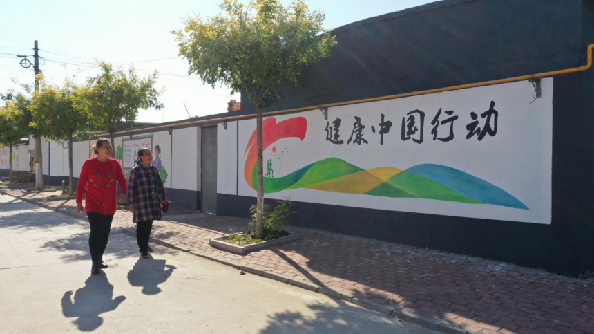 唐山市豐南區胥各庄鎮蠻子坨村村民正在欣賞“健康中國”牆體彩繪。 王碩攝