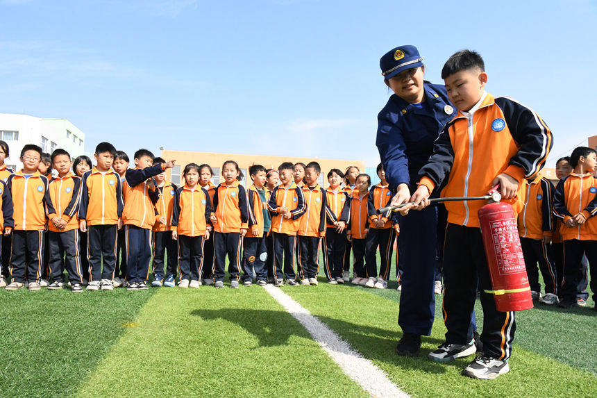 2022年10月12日，在河北省邯郸市广平县第四实验小学，消防救援人员教学生如何正确使用灭火器。程学虎摄