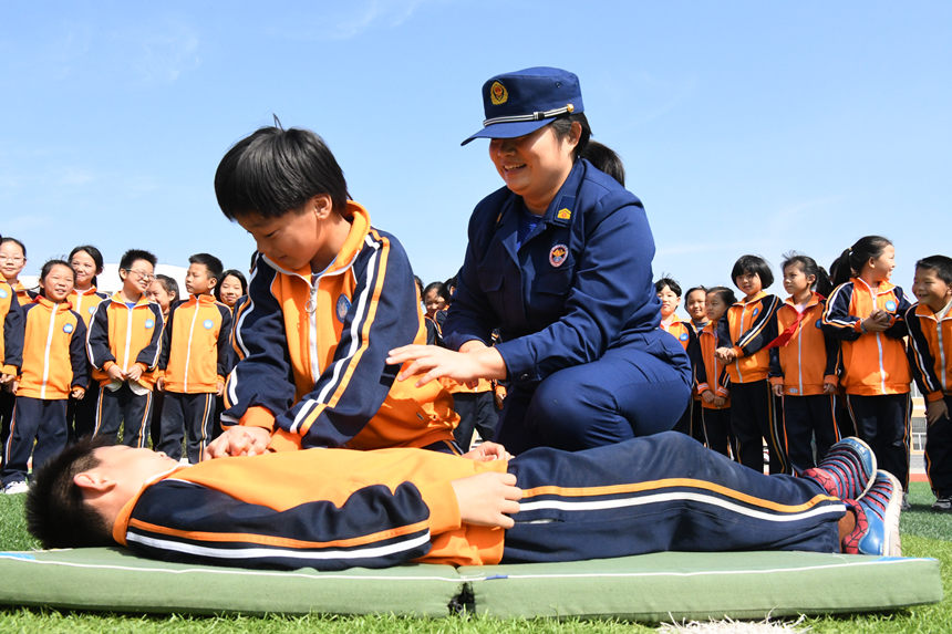 2022年10月12日，在河北省邯郸市广平县第四实验小学，消防救援人员在教给学生如何进行心肺复苏训练。程学虎摄