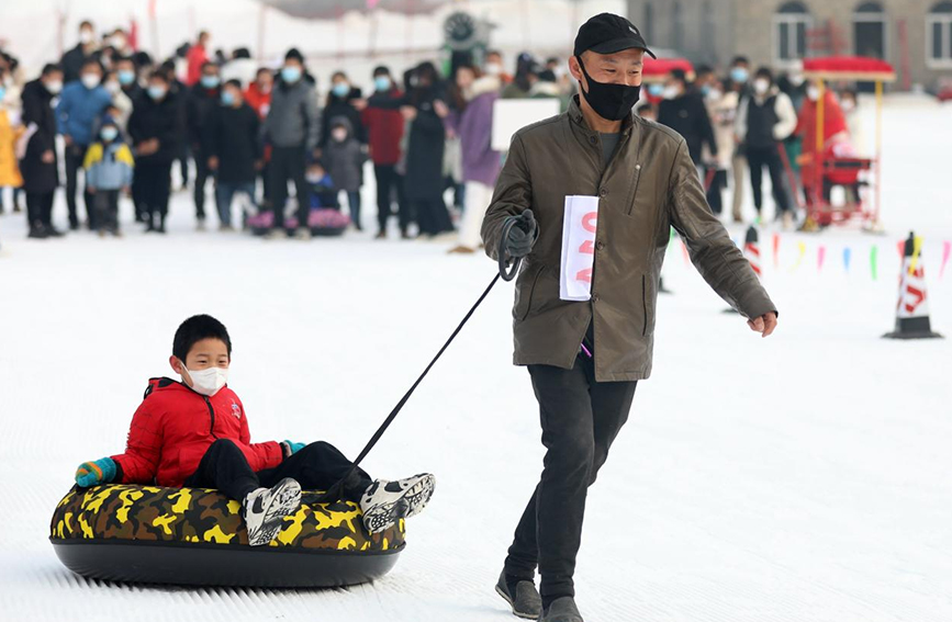 在沧县亲子冰雪趣味运动会上，正在进行亲子拉雪圈比赛。 周洋摄